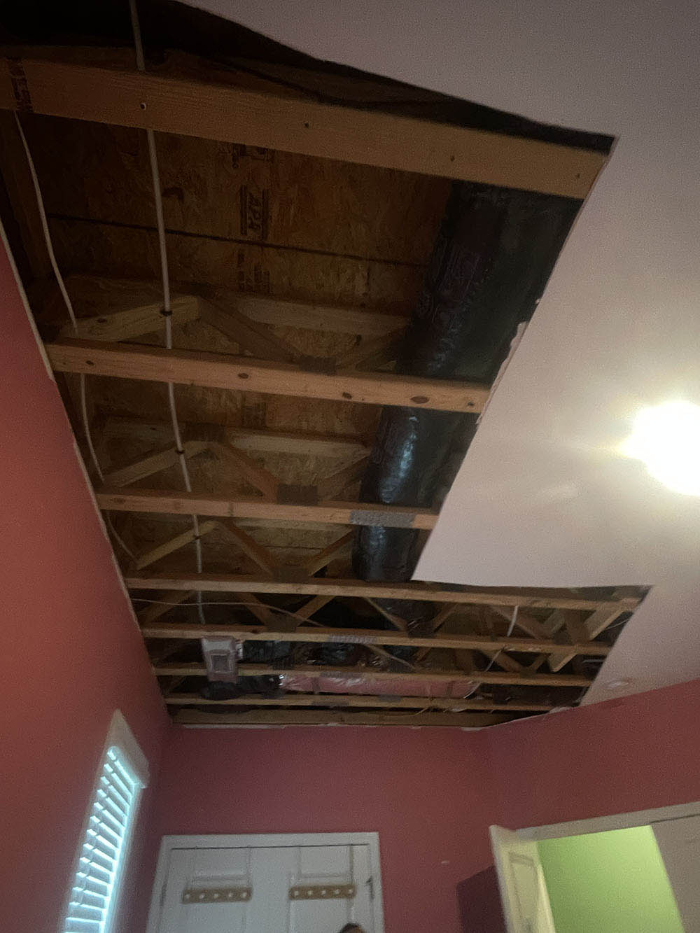 Exposed floor trusses, HVAC ductwork, and water piping after ceiling water mitigation cut